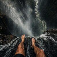 Point of view looking down a steep waterfall drop with rushing water and no barrier